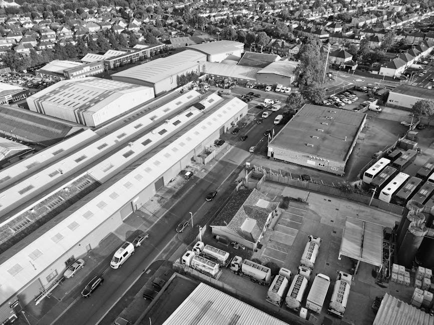 An aerial black-and-white photograph of a residential area showing a row of semi-detached houses with pitched roofs, front gardens, and driveways. The houses are closely spaced, with some featuring sm